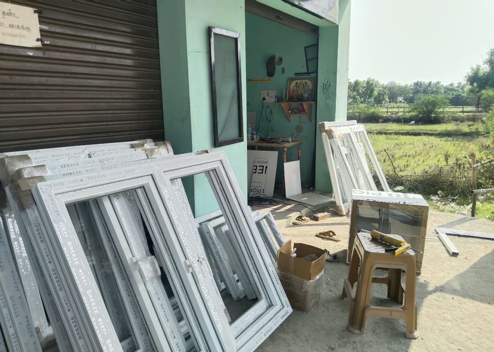 White UPVC window frames stacked outside the workshop, ready for site